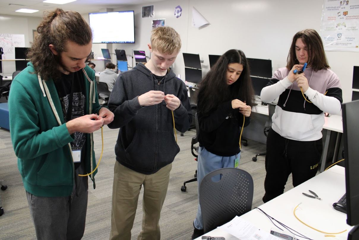 A group inmage of - from left to right - students Connor, Zach, Nishita, and Avery learning how to wire